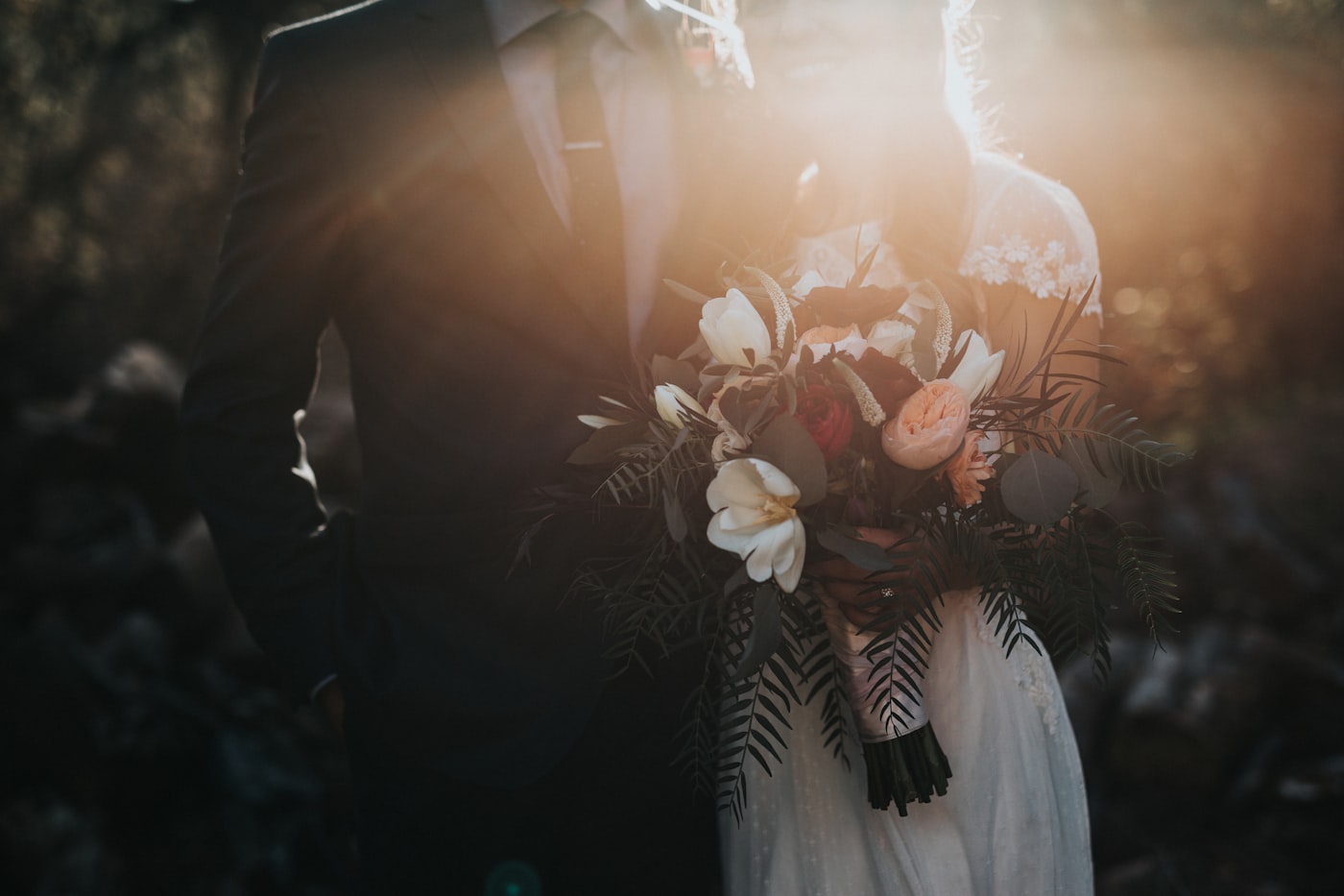 Mariage, bouquet et couple à contre-jour