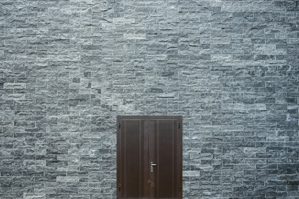 Porte sombre encastrée dans un mur de pierre brute